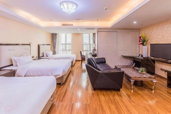 A hotel room with two beds, a sofa, a TV, and a balcony.