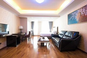Une chambre d’hôtel avec un lit, un canapé, un bureau et une télévision.