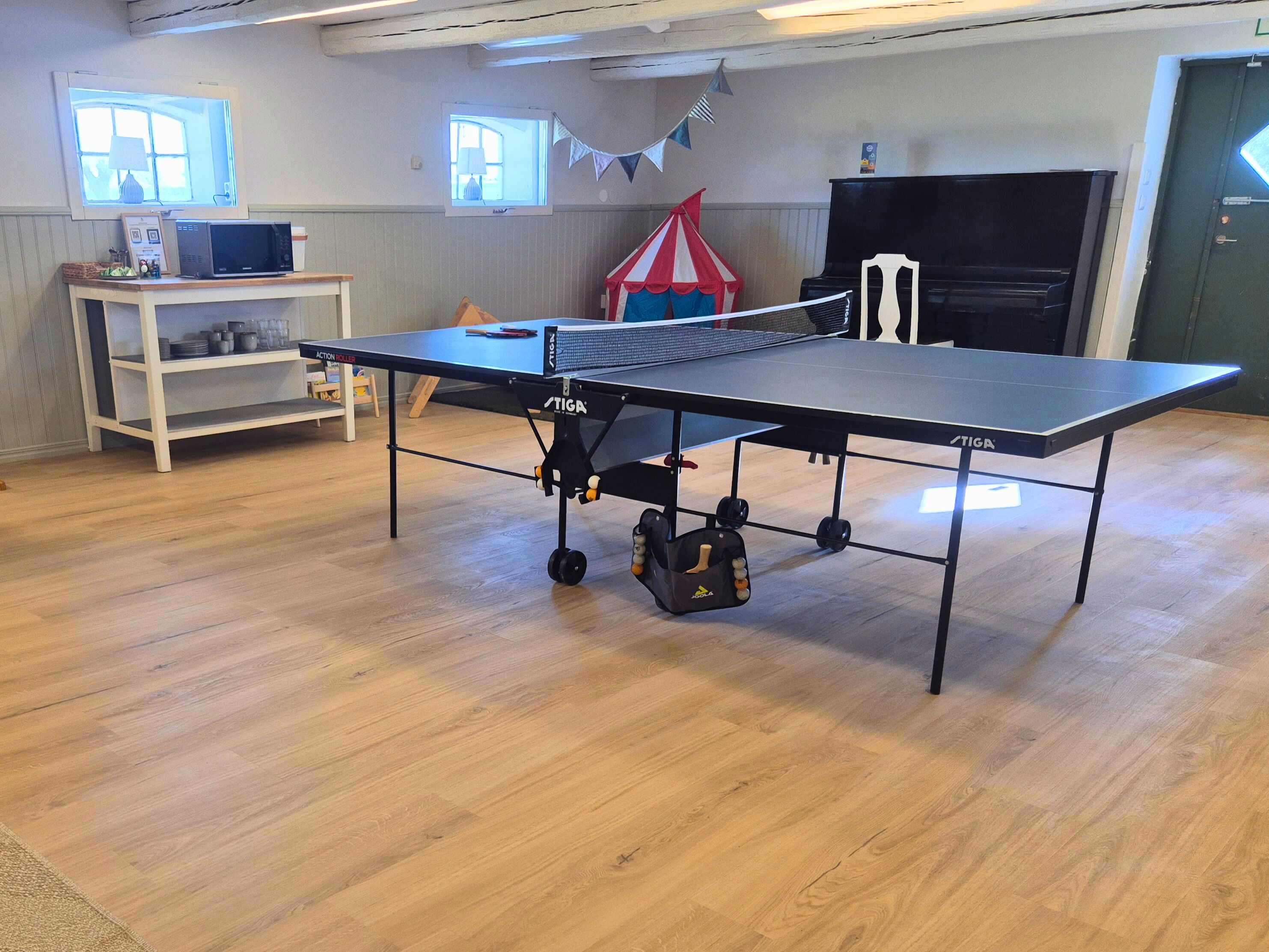 Ein Tischtennistisch auf Rollen, ein kleiner Tisch mit Küchenutensilien und eine rote und weiße, zeltartige Konstruktion.