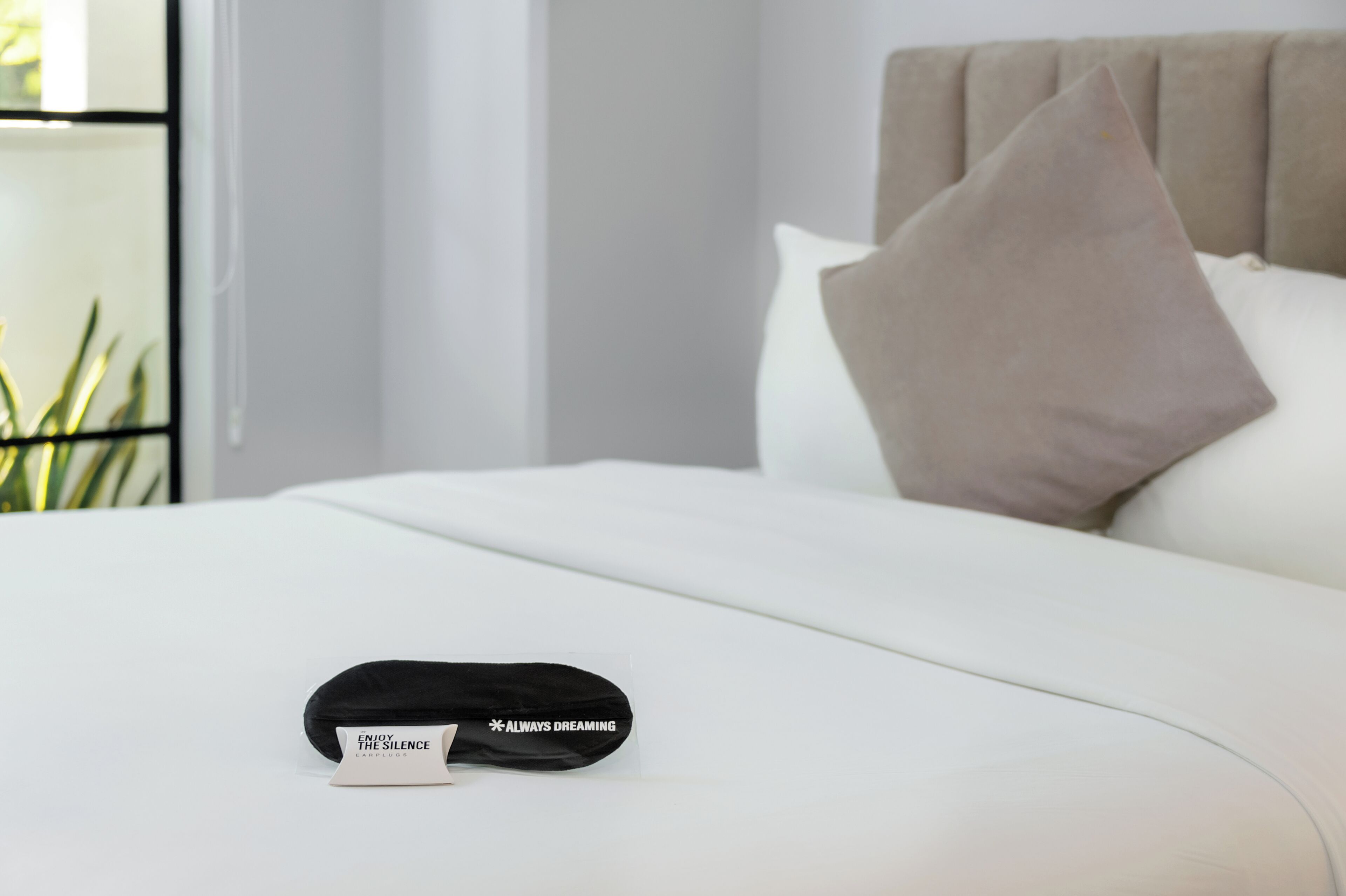 A neatly made bed with a pillow and a black object with text on it.