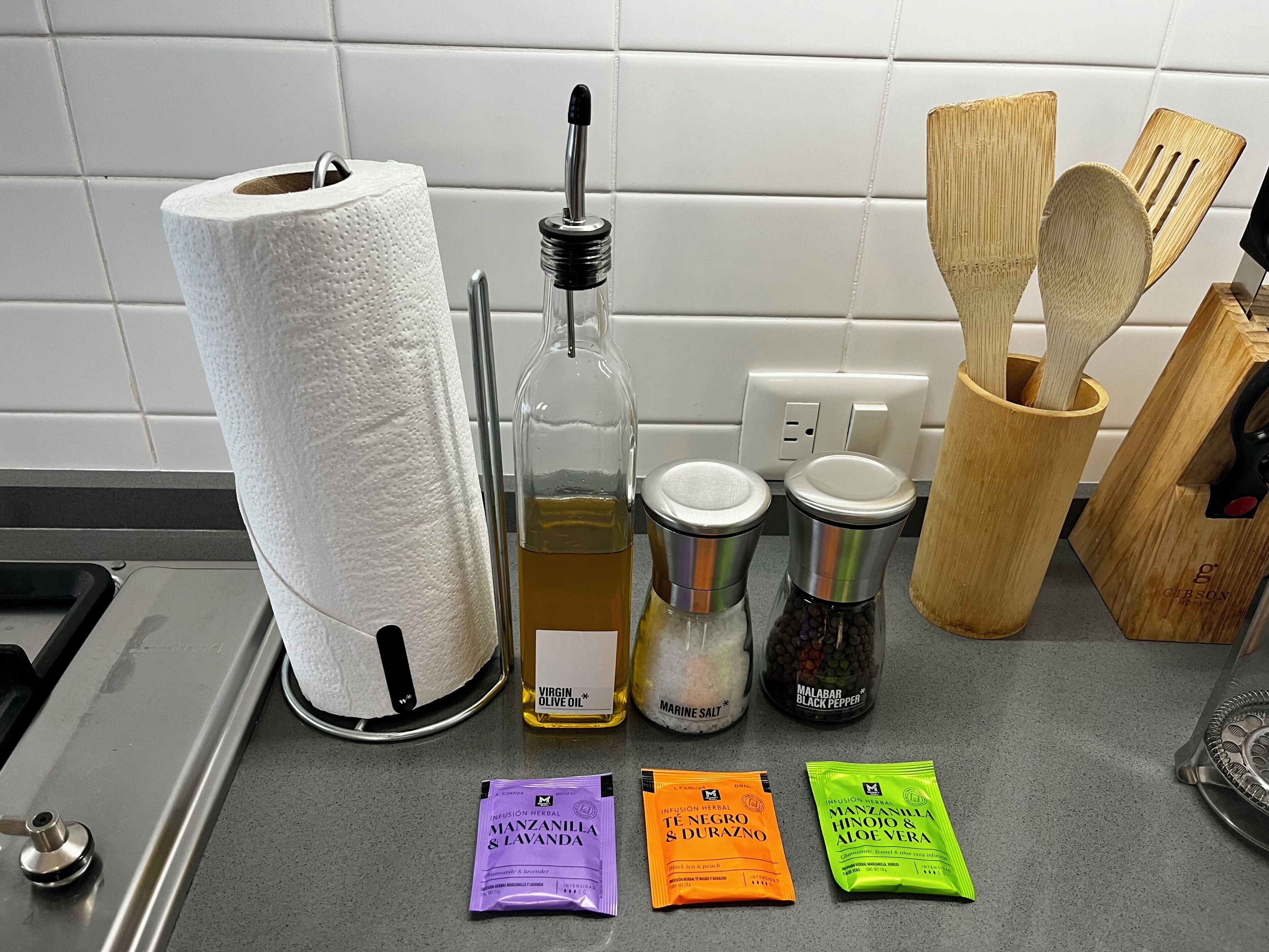 Keittiön työtasolla on paperipyyherulla, oliiviöljypullo, suola-astia, mustapippuripullo ja paketteja yrttiteetä.