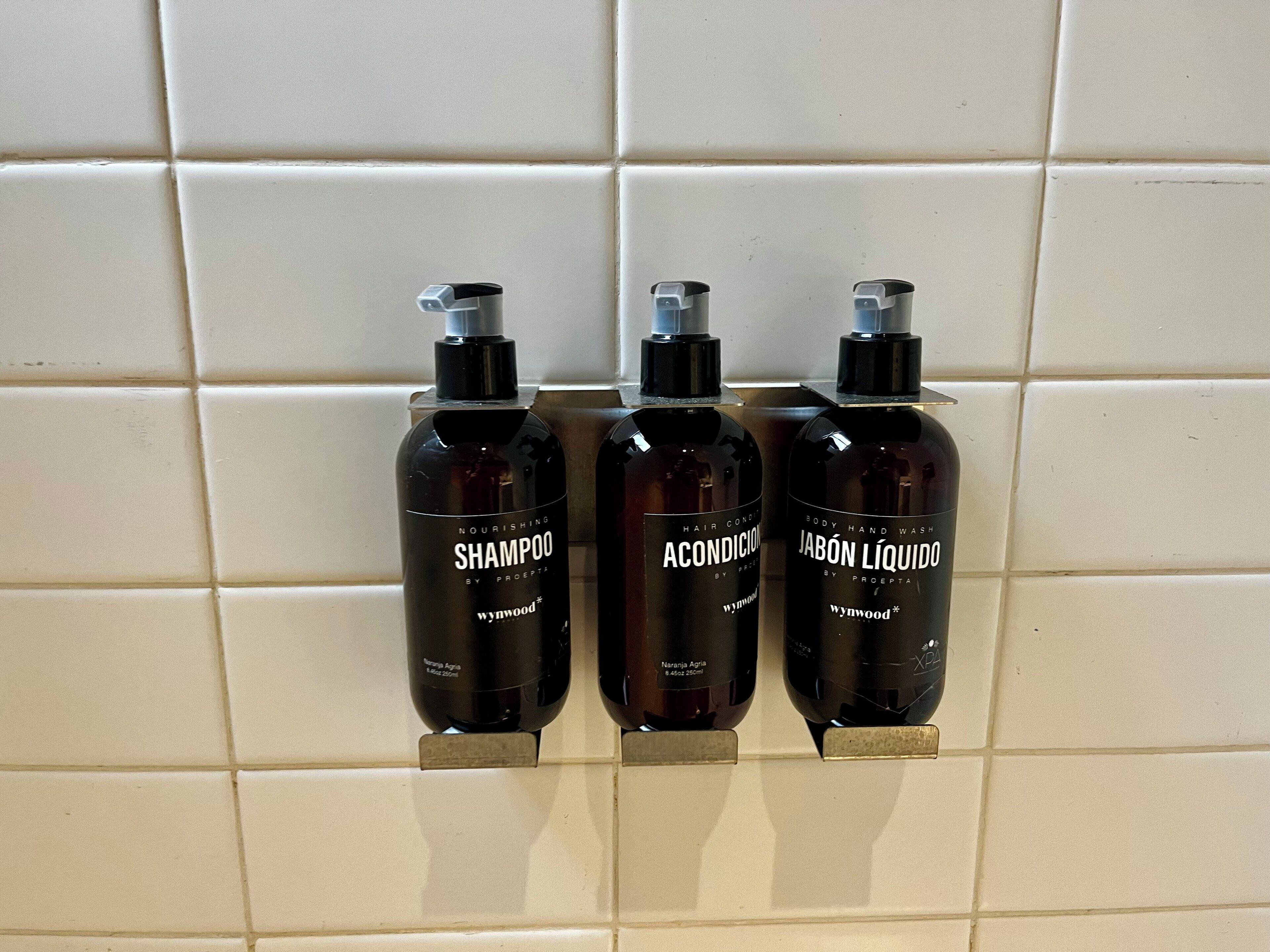 Three bottles of hair care products on a tiled wall.