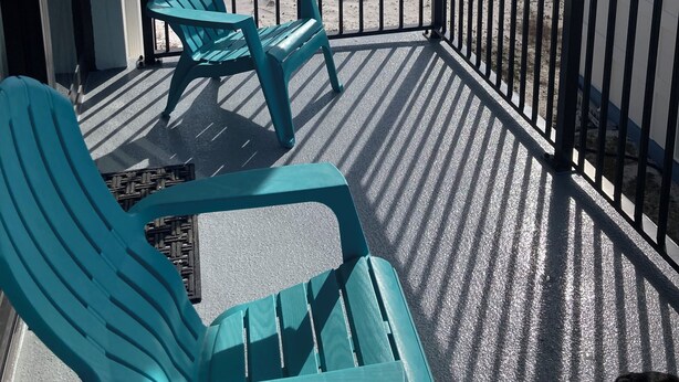 A balcony with two turquoise chairs, a view of the beach, and a railing. - Forget your worries in this spacious and serene space. (Gulf Shores)