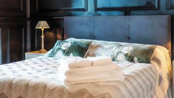 A neatly made bed with patterned bedding and decorative pillows, a bedside lamp, and a dark wood-paneled headboard.