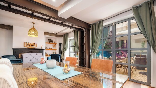 A modern living room with a glass-top dining table, a fireplace, and a view of the outdoor patio. - Oakmoon House (Faro)