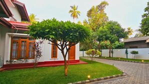 A residential property with a well-maintained lawn, a small tree, and a paved driveway.