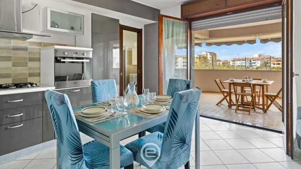 Een moderne keuken met een eethoek, een balkon met tafel en stoelen, en uitzicht op de omliggende gebouwen.