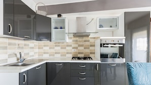 Een moderne keuken met donkere kastjes, een gasfornuis, een inbouwoven en een magnetron.
