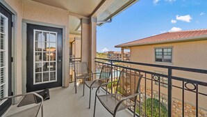 A balcony with a door, two chairs, and a view of a residential area with a swimming pool. - Close To Disney, Clubhouse With Gym, Communal Pool (Davenport)