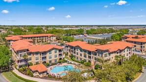 A resort with multiple buildings, a swimming pool, and a clear blue sky. - Close To Disney, Clubhouse With Gym, Communal Pool (Davenport)