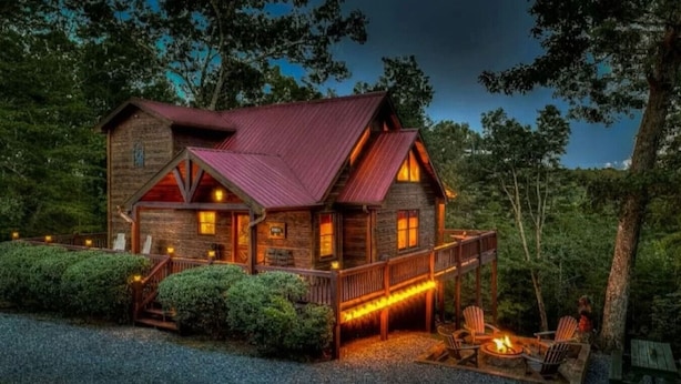 Une cabane rustique avec une façade en bois, une véranda et un foyer extérieur.