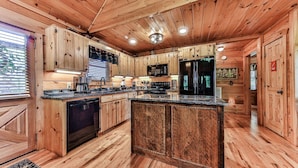 L’intérieur d’un chalet en bois comprend une cuisine équipée de meubles en bois, d’un îlot central et d’un réfrigérateur.