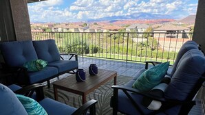 Un espacio de descanso techado con mobiliario azul y vistas a un barrio residencial y montañas.