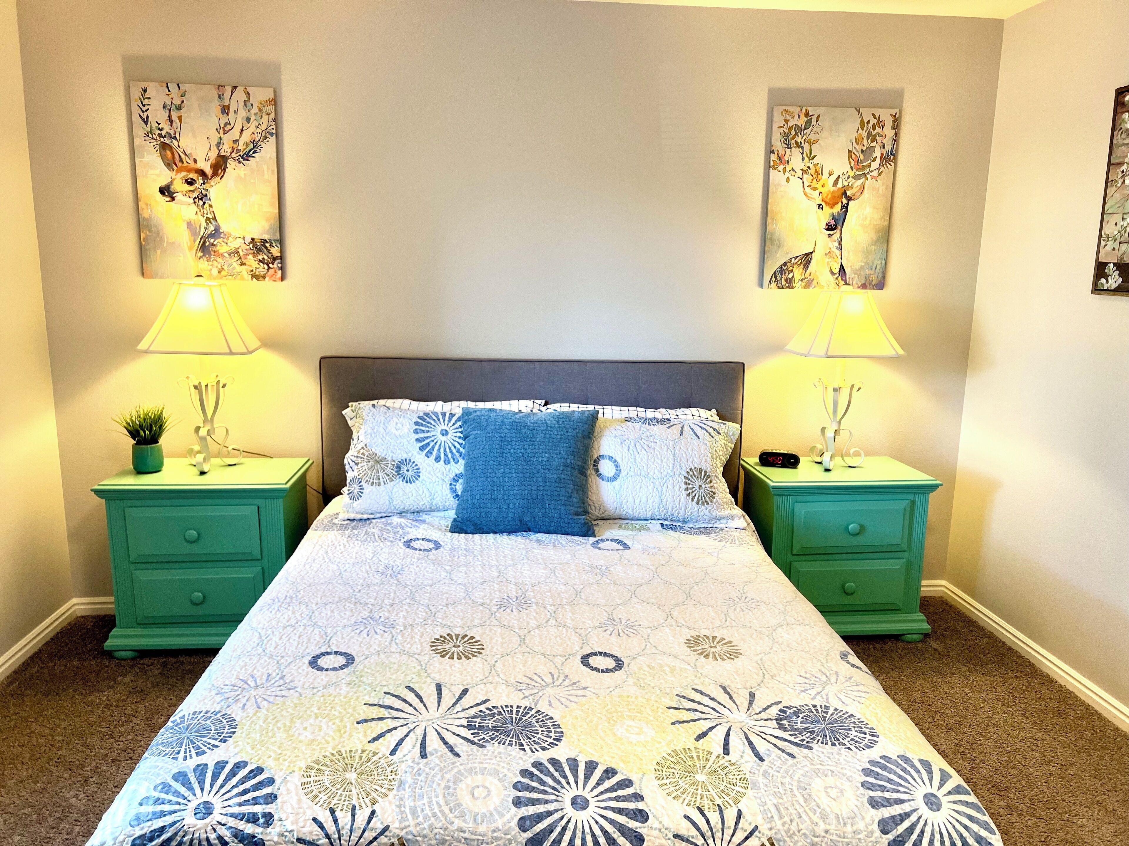Ein Schlafzimmer mit einem Bett, zwei Nachttischen, zwei Lampen und zwei an der Wand befestigten Bildern.
