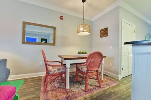 Un coin repas avec des chaises en osier, une table en bois et un luminaire suspendu.