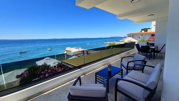 Un balcon avec vue sur la mer, des sièges d’extérieur et une table.