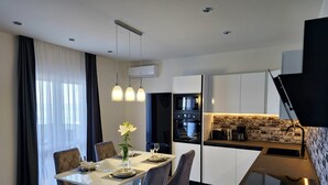 Une cuisine moderne avec un coin repas, comprenant une table blanche mise avec des assiettes, des verres et un vase de fleurs.