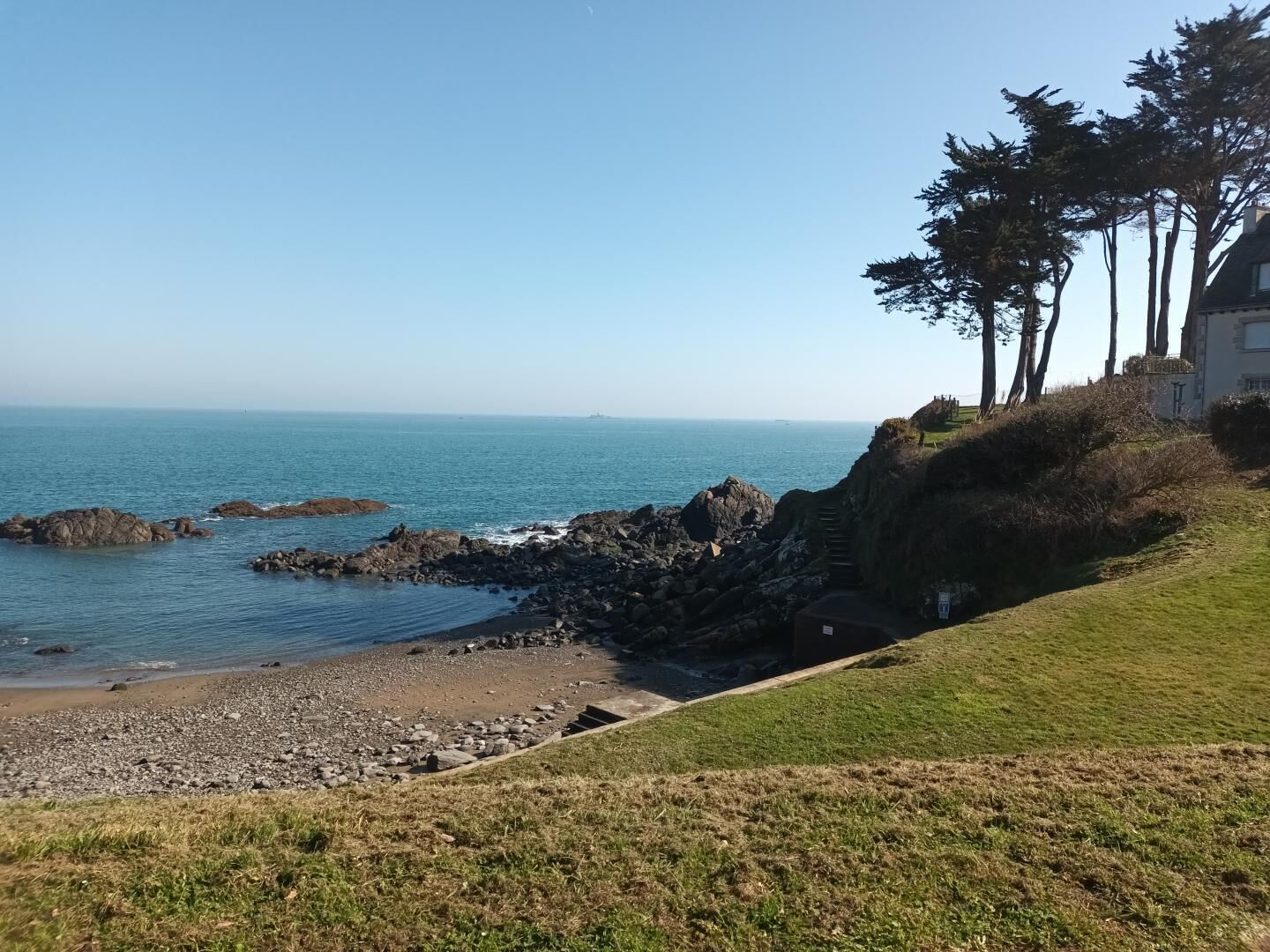 Une vue sur la côte, avec une pente herbeuse qui descend vers un rivage rocheux.