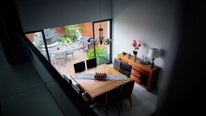 A modern dining area with a wooden table, chairs, and a view of the outdoor patio. - Stylish family boutique house, 10 minutes from downtown Oaxaca. (Oaxaca City)