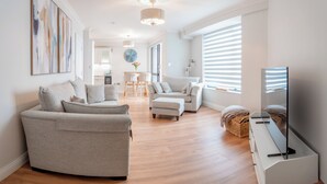 Un salon moderne avec un canapé, un pouf et un meuble pour la télévision.