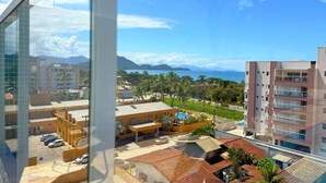 A hotel with a pool, a view of the sea, and a mountainous landscape in the background. - Apt 109 - new, cozy, 150 meters from the beach, we have other apartments. (Ubatuba)
