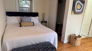 A neatly arranged bedroom with a bed, bedside table, and a small bench.
