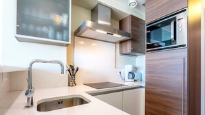 Una cocina moderna con un lavamanos de acero inoxidable, un microondas y armarios de madera.