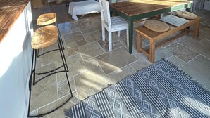 Un interior rústic amb taula de dinar de fusta, una escala i un penjoll.