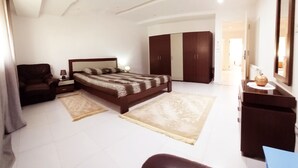 Un dormitorio con cama, mesitas de noche, una silla, un armario y un aparador.