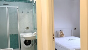 Un bagno con doccia, WC, lavatrice e lavandino.