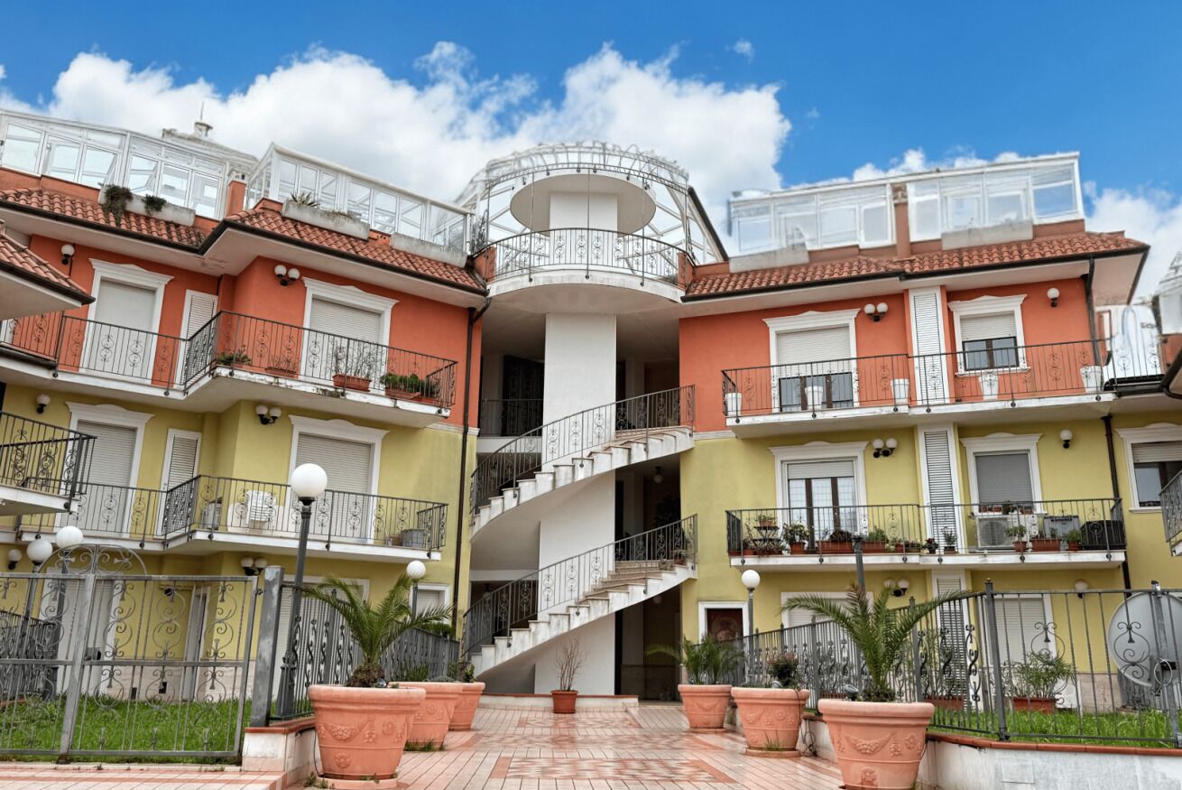 A multi-story residential building with balconies, a central spiral staircase, and a courtyard.