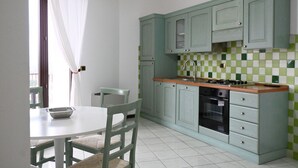 Una cucina con mobili verdi, un piano di lavoro bianco e un rivestimento a piastrelle.