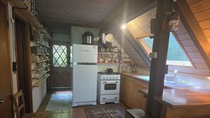 Eine Küche mit Holzausstattung, einem Kühlschrank, einem Herd und einem Fenster mit Blick.