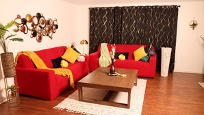A living room with a red sofa, a wooden coffee table, and a patterned curtain. - Work Play Stay Pet-friendly With Foosball (Aubrey)