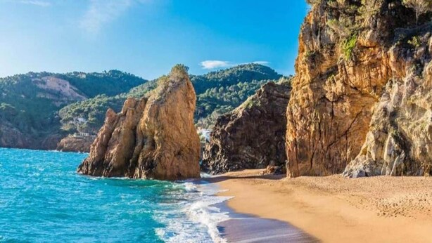 Una spiaggia costiera con scogliere rocciose e una battigia sabbiosa.