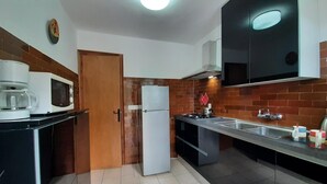 Una cucina compatta con forno a microonde, frigorifero e lavello.
