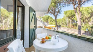 Un balcone con tavolo e sedie bianche e una ciotola di frutta.
