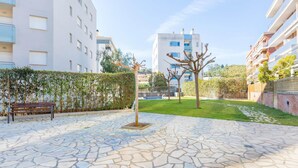 Un patio con suelo de piedra, un banco y un árbol.