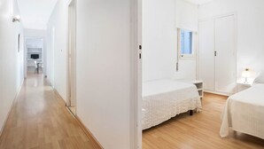 A bedroom with two beds, a window, and a desk.