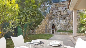 Un área de comedor al aire libre con muros de piedra, una chimenea y vistas a un edificio de piedra.