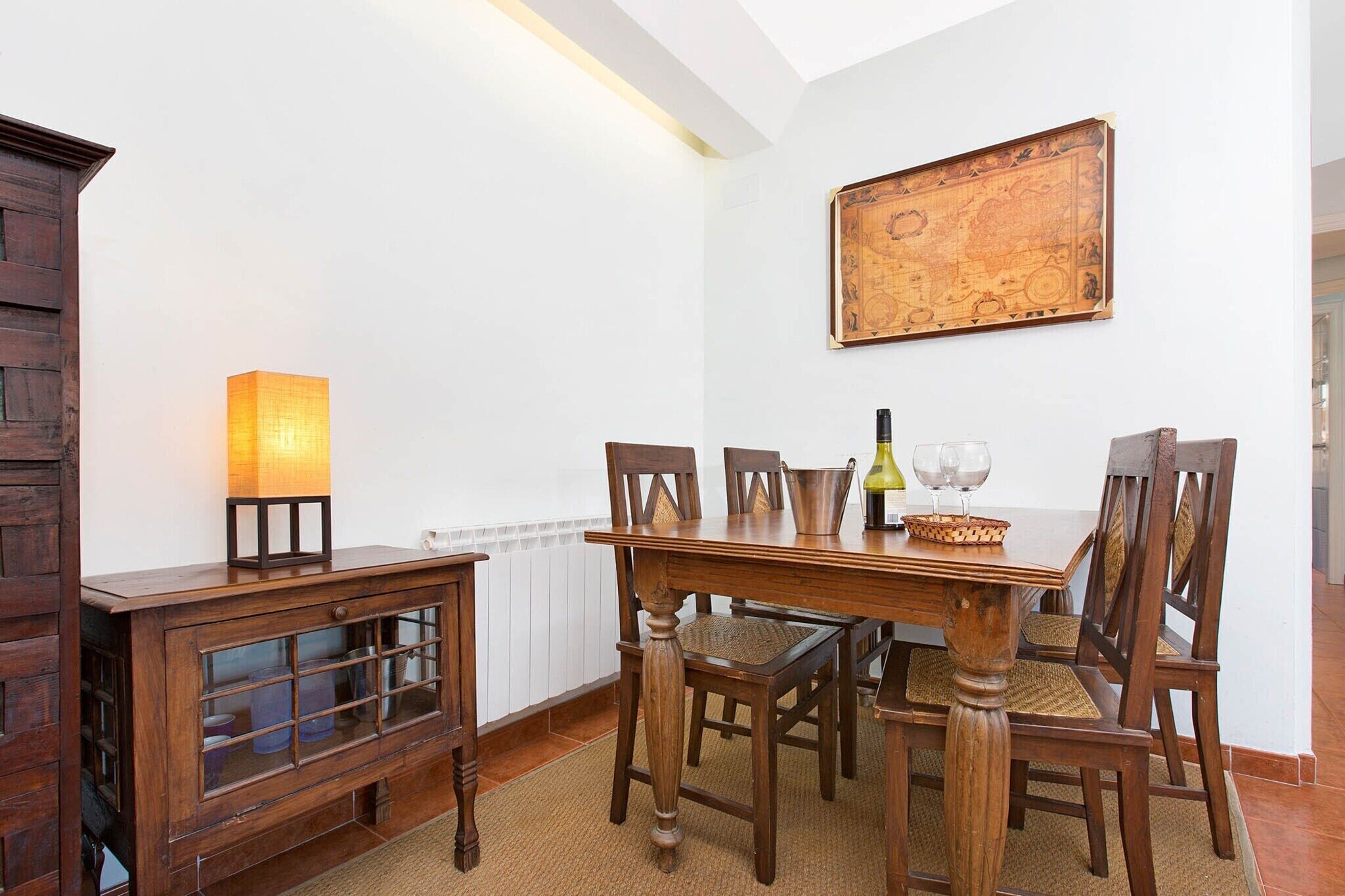 Un coin repas avec une table en bois, des chaises, une lampe et une carte accrochée au mur.