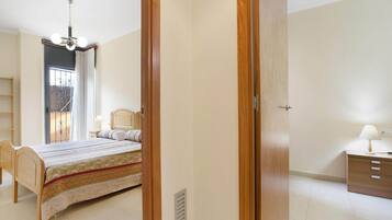 Een slaapkamer met een bed, nachtkastje, stoel, kledingkast en een raam met gordijnen.