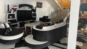 Ett modernt vardagsrum med en böjd, svart soffa, en platt-TV och en trappa som leder upp till en övre våning.