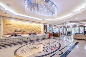 A hotel lobby with a reception desk, a large chandelier, a patterned floor, and a seating area. - Guo Tai Yue Gang Hotel (Zhaosu)