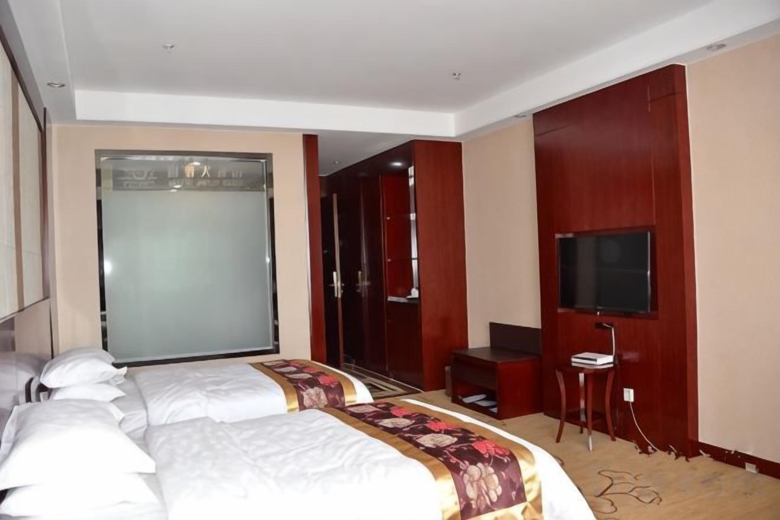 A hotel room with a bed, a TV, a wardrobe, and a bathroom.