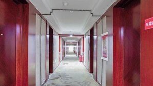 Un couloir aux murs recouverts de lambris en bois et doté d’un sol à motifs, qui mène à une porte au fond.