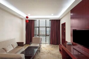 A modern living room with a sofa, a coffee table, a TV, and a large window with curtains.
