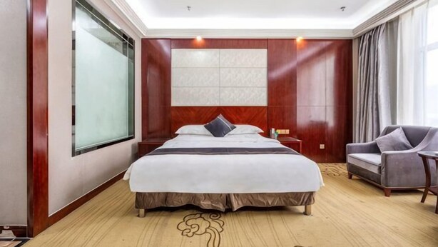 Een hotelkamer met een groot bed, een bank, een nachtkastje en een raam.