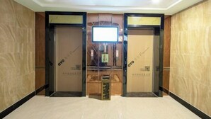 Een hotel lobby met twee liften, een receptiebalie en een vitrine.