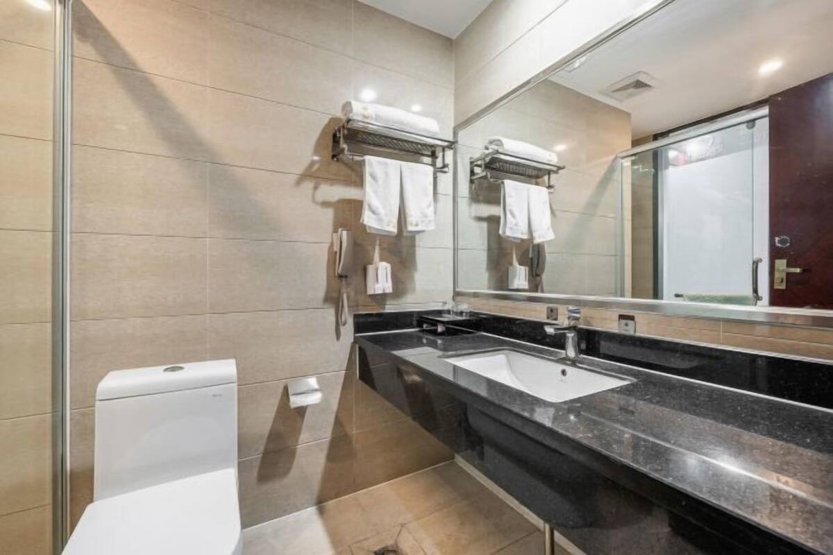 A modern bathroom with a glass shower enclosure, a white toilet, and a black countertop sink.